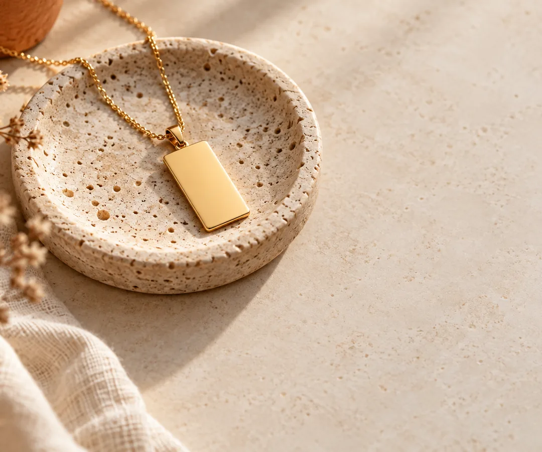 A gold pendant necklace on a stone dish